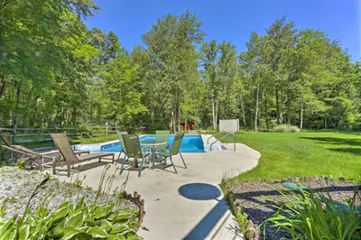 a patio with a table and chairs next to a pool at Decked-Out Home Hot Tub, Pool, Fire Pit and More! in Monroe