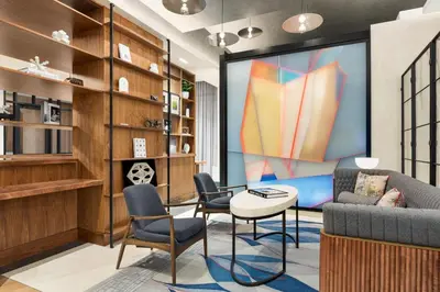 a living room with a couch and chairs and a large screen at Le Meridien New York, Fifth Avenue in New York