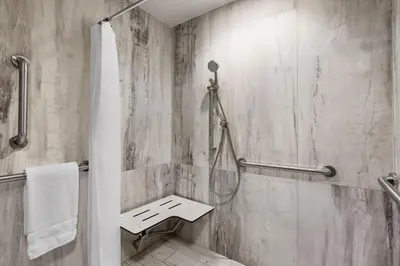 a bathroom with a shower with a bench in it at Le Meridien New York, Fifth Avenue in New York