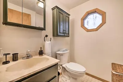 a bathroom with a sink and a toilet and a window at Walk to Arrowhead Lake Cabin with Private Hot Tub! in Pocono Lake