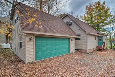a garage with a green garage door on a house at Walk to Beach Lakefront Pocono Escape with Fire Pit in Pocono Lake