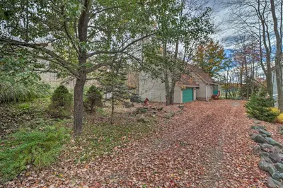 a house with a tree and a driveway at Walk to Beach Lakefront Pocono Escape with Fire Pit in Pocono Lake