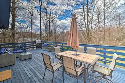 a patio with a table and an umbrella on a deck at 6 Mi to Camelback Slopes! Home with Game Room in Long Pond