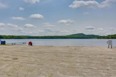a person standing on a beach near a body of water at Walk to Beach Pocono Lake Cabin with Pool Access! in Pocono Lake