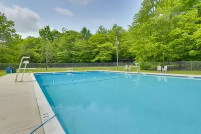 a large blue swimming pool with chairs and trees at Walk to Beach Pocono Lake Cabin with Pool Access! in Pocono Lake