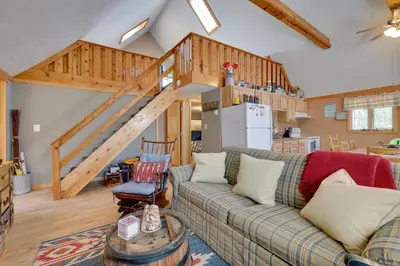 a living room with a couch and a staircase at Walk to Beach Pocono Lake Cabin with Pool Access! in Pocono Lake