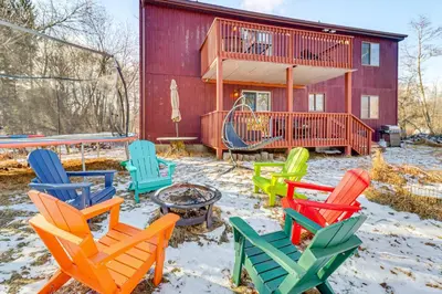 a group of colorful chairs in front of a house at Private Spa, Fire Pit and Deck Poconos Home! in Long Pond
