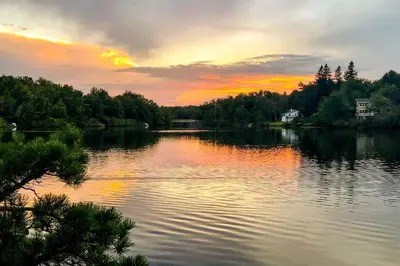 a view of a lake with a sunset in the background at Private Spa, Fire Pit and Deck Poconos Home! in Long Pond