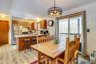 a kitchen and dining room with a wooden table and chairs at Private Spa, Fire Pit and Deck Poconos Home! in Long Pond