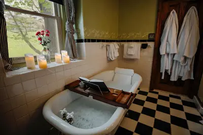 a bath tub in a bathroom with a window and candles at Galvanized America Inn & Art Gallery in Doylestown