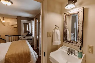 a bathroom with a sink and a bed and a mirror at Galvanized America Inn & Art Gallery in Doylestown
