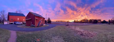 a red barn with a car parked next to a road at Galvanized America Inn & Art Gallery in Doylestown