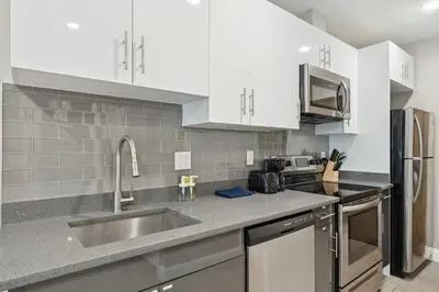 a kitchen with white cabinets and a stainless steel sink at Stay at Luna on Callowhill in Philadelphia