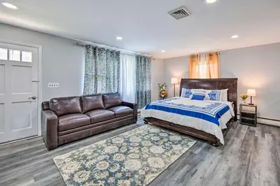 a bedroom with a bed and a leather couch at 1 Mi to Hersheypark Family Home with Game Room! in Hershey