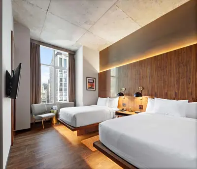 a hotel room with two beds and a desk at Grayson Hotel in New York