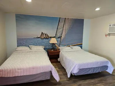 two beds in a room with a painting of a sailboat at Stardust Motel in Duncannon