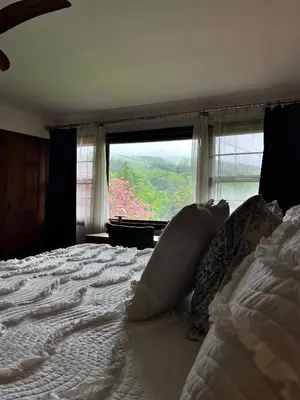 a bedroom with a large bed with a large window at The Blue House On The Hill Catskills—Views in Claryville