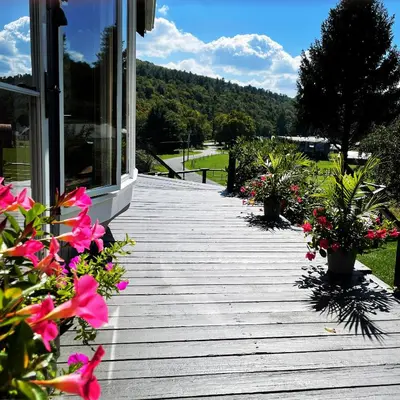 a wooden walkway with flowers on a house at The Blue House On The Hill Catskills—Views in Claryville