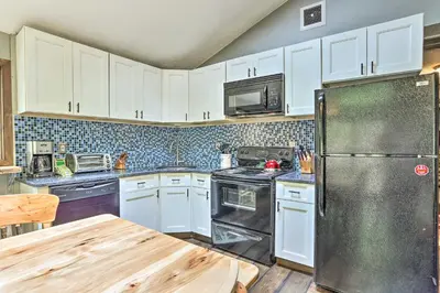 a kitchen with white cabinets and a stainless steel refrigerator at Walk to Lake and Beach Pocono Cabin with Fire Pit in Pocono Lake