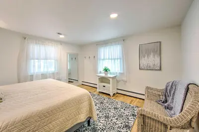 a bedroom with a bed and a chair and windows at 3 Mi to Dutch Wonderland Serene Home with Deck in Lancaster