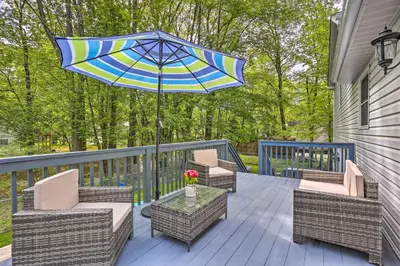 a patio with chairs and a table with an umbrella at 2 Game Rooms! Family Poconos Home 9 Mi to Slopes in Pocono Summit