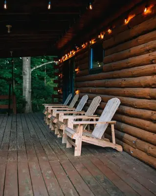 a row of chairs sitting on a porch of a log cabin at Afton Cabin in Afton