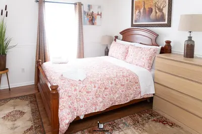 a bedroom with a bed with a wooden headboard at Beautifully Designed & Spacious Apartment in Newark 10mins from EWR Airport, Close to NYC and Beth Israel Hospital in Newark