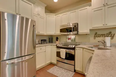 a kitchen with white cabinets and a stainless steel refrigerator at Half-Mi to Big Boulder Lake Townhome with Deck! in Lake Harmony