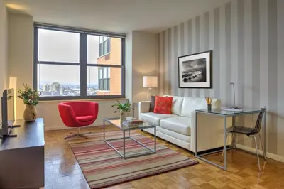 a living room with a couch and a red chair at Furnished Quarters at Grove Pointe in Jersey City