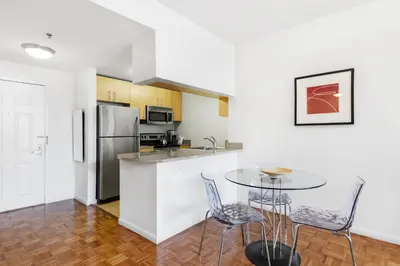 a kitchen with a table and chairs and a refrigerator at Furnished Quarters at Grove Pointe in Jersey City