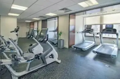 a gym with several tread machines in a room at Furnished Quarters at Grove Pointe in Jersey City