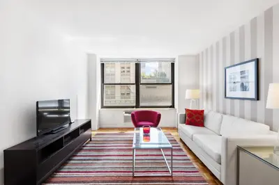 a living room with a white couch and a red chair at Furnished Quarters at Grove Pointe in Jersey City