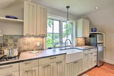 a kitchen with white cabinets and a sink and a window at Barn-Like Studio Suite with Flowering Garden! in Titusville
