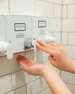a woman is washing her hands in a public restroom at Sosuite at French Quarters - Rittenhouse Square in Philadelphia