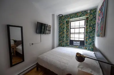 a bedroom with a bed and a mirror and a window at The Flat NYC in New York