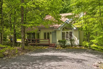 a green house with a gravel driveway in front of it at Deck and Resort Amenities Pocono Lake Home in Pocono Lake