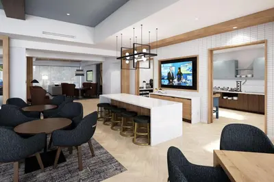 a living room with tables and chairs and a kitchen at Staybridge Suites Wilmington Downtown by IHG in Wilmington