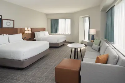 a hotel room with two beds and a couch at Staybridge Suites Wilmington Downtown by IHG in Wilmington