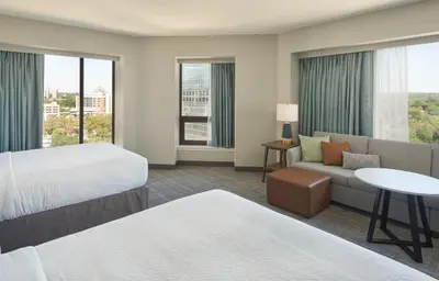 a hotel room with two beds and a couch at Staybridge Suites Wilmington Downtown by IHG in Wilmington