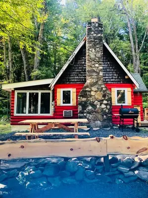 a small red cabin with a picnic table in front of it at Bear Cottage in Birchwood Lakes