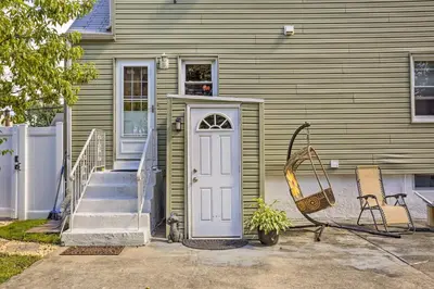 a green house with a blue door and a porch at Saddle Brook Studio with Patio - Near NYC! in Saddle Brook