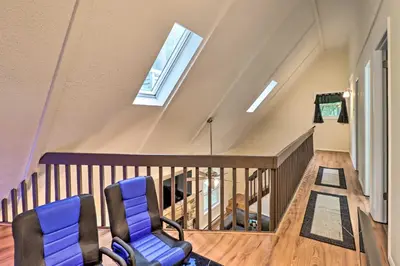 a attic room with two chairs and a staircase at 7 Mi to Lake Harmony Home with Furnished Deck! in Albrightsville