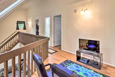 a living room with a staircase and a tv at 7 Mi to Lake Harmony Home with Furnished Deck! in Albrightsville
