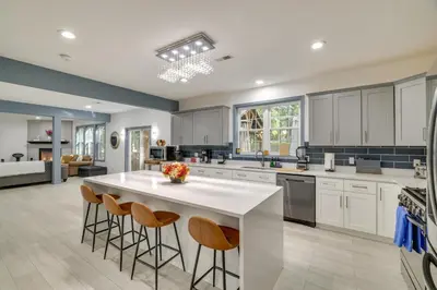a kitchen with white cabinets and a large island with bar stools at Game Room and Home Theater! Immaculate Poconos Lodge in Albrightsville