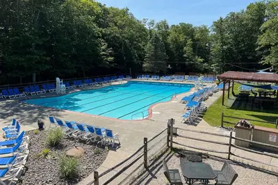 a large swimming pool with blue chairs at Near Skiing and Hiking Gouldsboro Home with Hot Tub in Gouldsboro