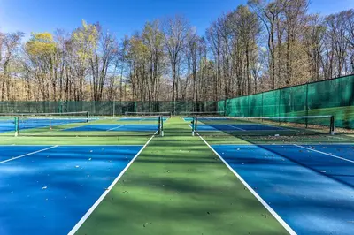 two tennis courts with trees in the background at Near Skiing and Hiking Gouldsboro Home with Hot Tub in Gouldsboro