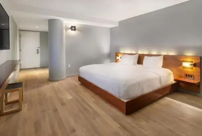 a bedroom with a large white bed and wooden floors at Truss Hotel Times Square in New York