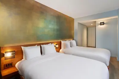 two beds in a hotel room with a painting on the wall at Truss Hotel Times Square in New York