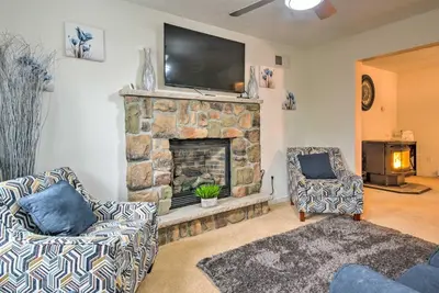 a living room with a stone fireplace with a flat screen tv at Jacuzzi and Resort Amenities Tobyhanna Family Home! in Tobyhanna