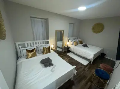 a bedroom with two beds with white sheets and gold pillows at THE ROOFTOP OASIS in Philadelphia